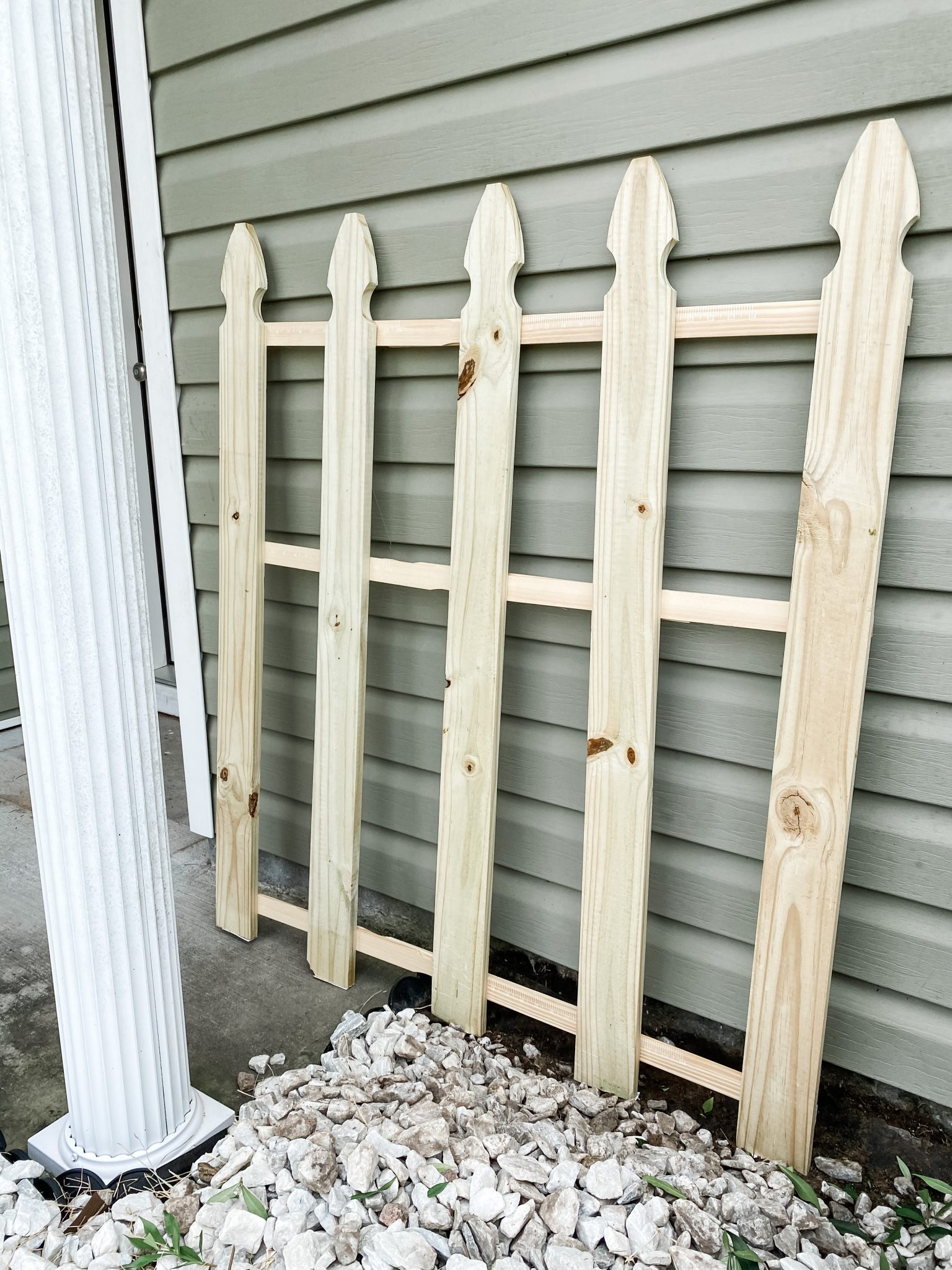 Unfinished DIY wood picket fence used as a backdrop for the fall porch display
