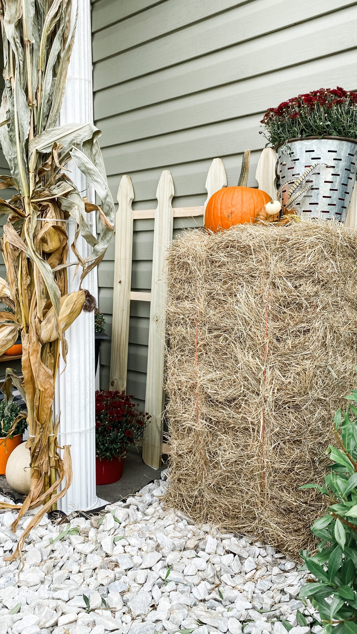 Tall cornstalk beside the porch pillar adding height to the outdoor fall decor