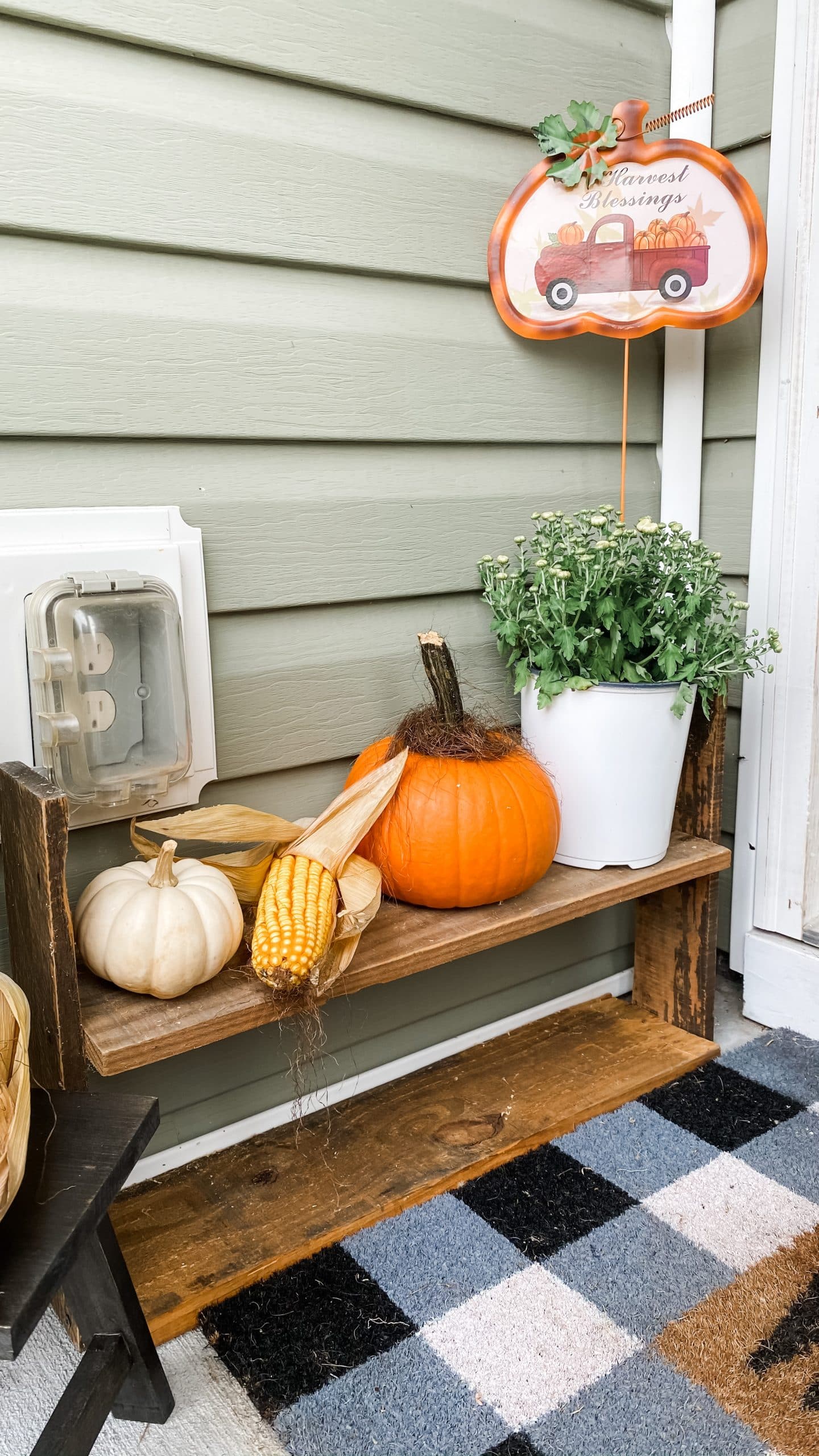 Small wood shelf styled with a fall mum, pumpkins, corn and Dollar Tree truck decoration