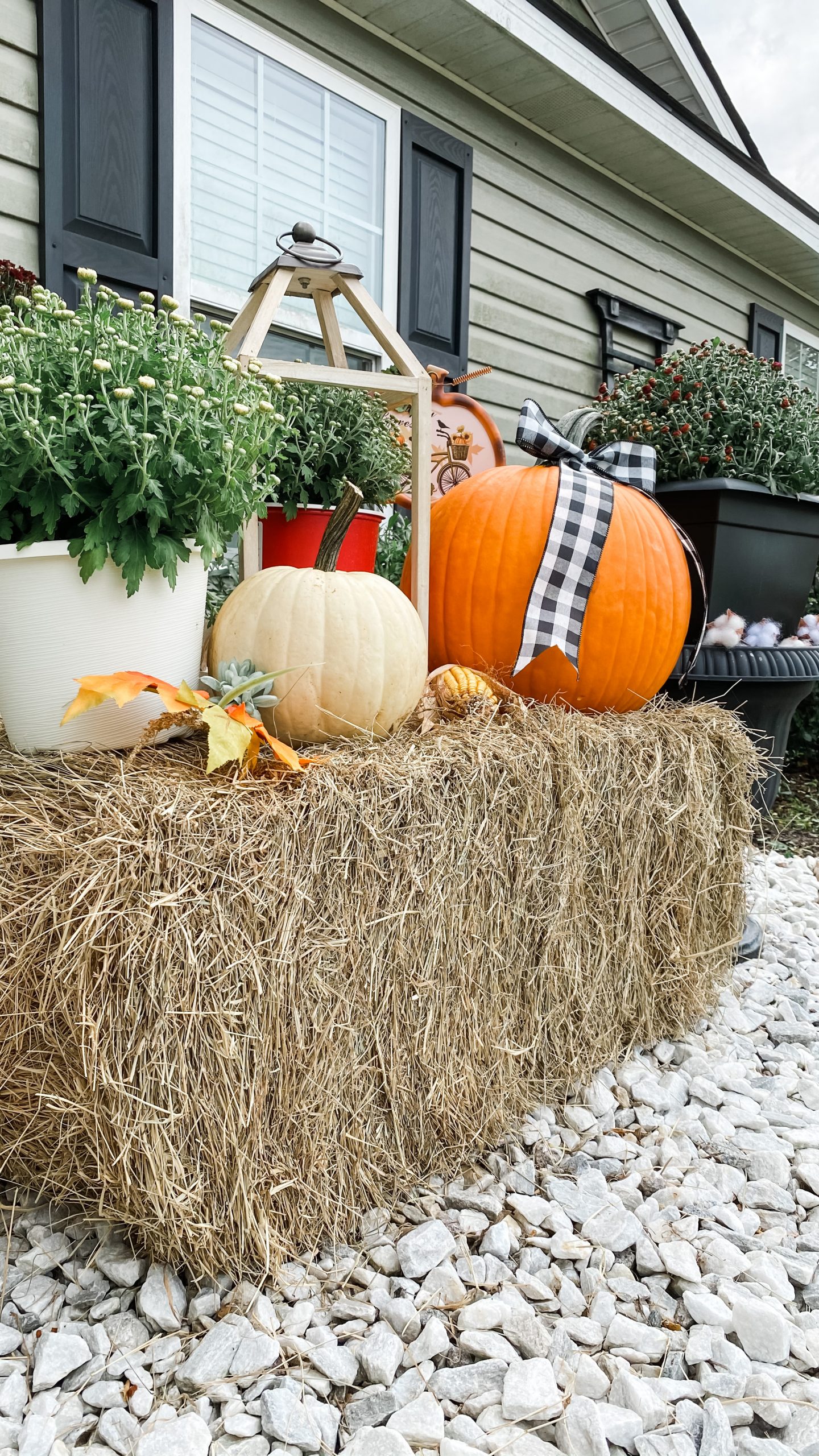 Hay bale used to create height for pumpkins, mums and layered fall porch decorations