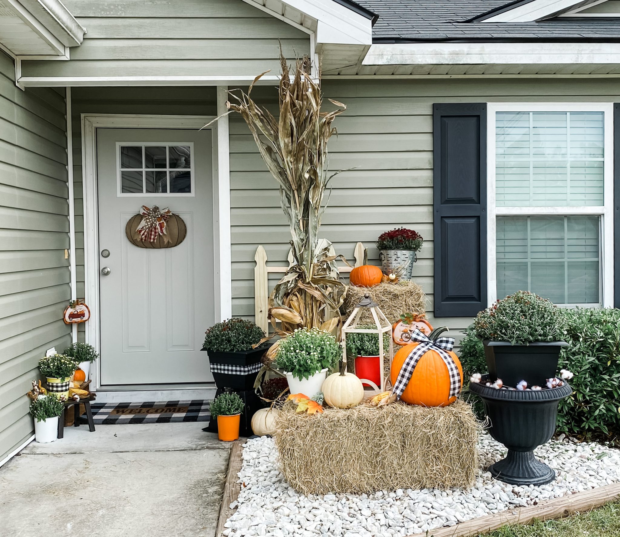 Fall front porch makeover decorated with mums, pumpkins, hay bales, cornstalks and handmade fall decor