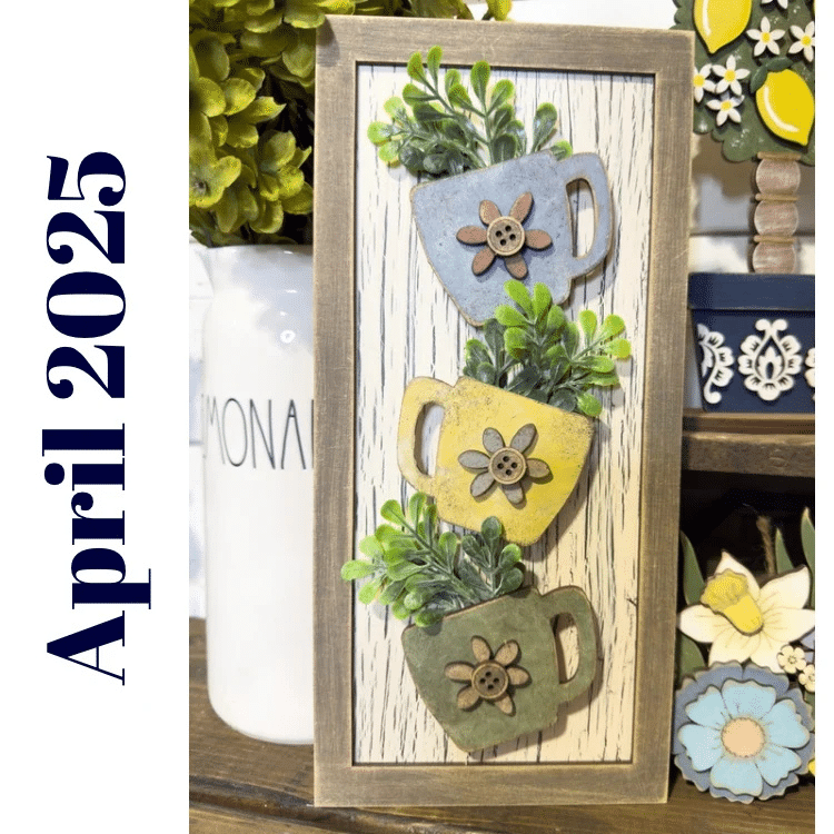 stacked wooden teacups with greenery on a framed sign