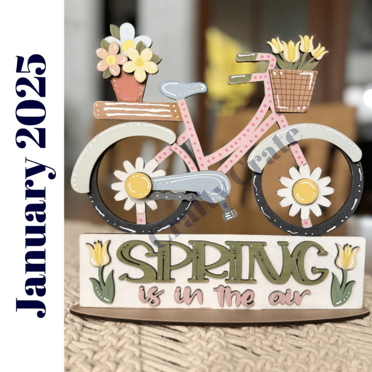 pink bike with daisies on the wheels and sign reading Spring is in the air painted and assembled for display