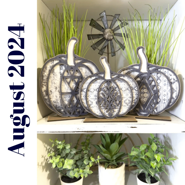 three coordinating black and white pumpkins painted and displayed on a white shelf with greenery