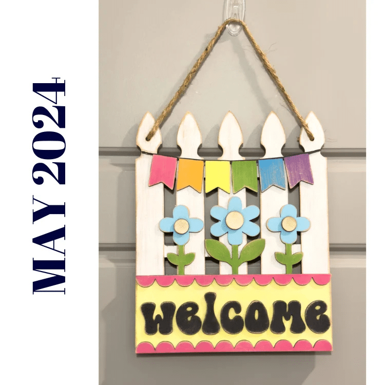 white picket fence hanging welcome sign with flowers and banner