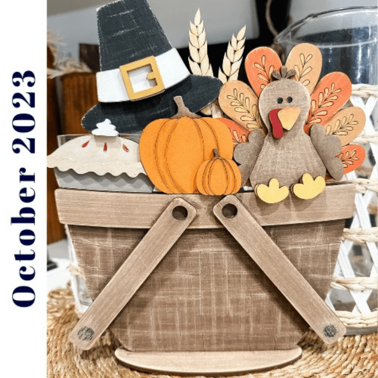 thanksgiving insert with turkey, pumpkin, pilgrim hat, feathers, pumpkins, and pie displayed in a wooden picnic basket