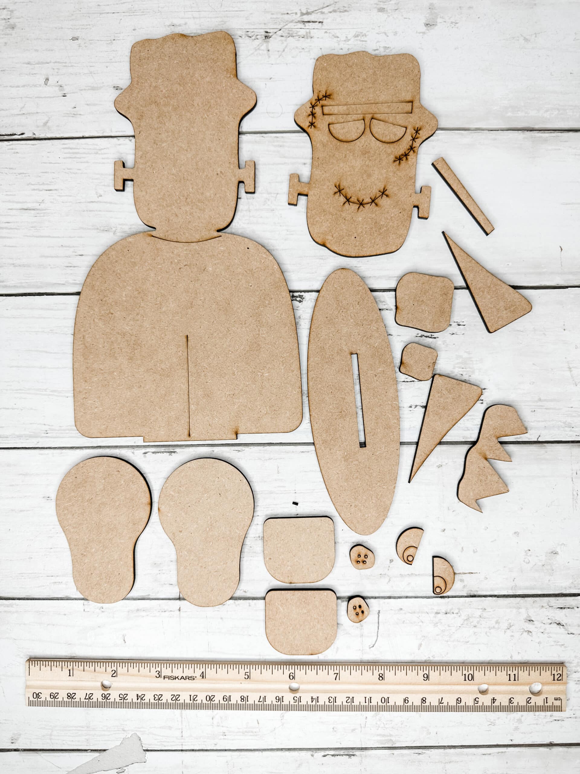 unpainted unassembled frankenstein diy craft kit pieces displayed in a single layer on a neutral background