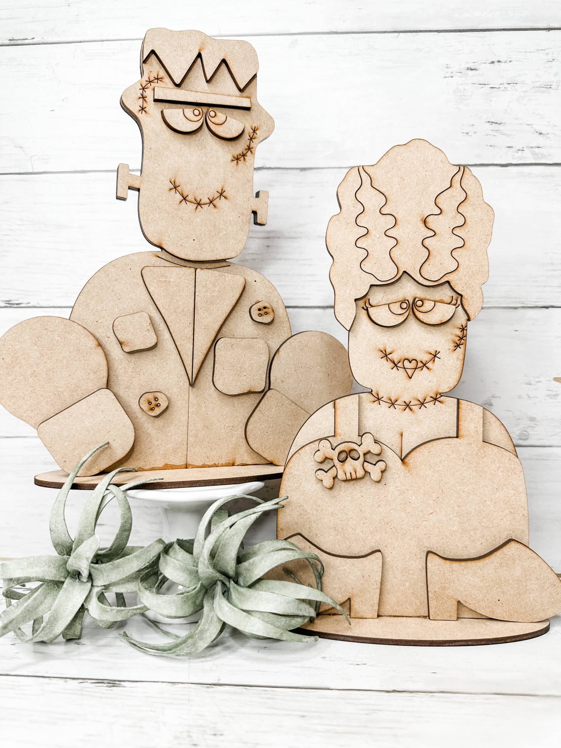 unpainted assembled frankenstein and bride of frankenstein diy craft kits displayed in front of a neutral background